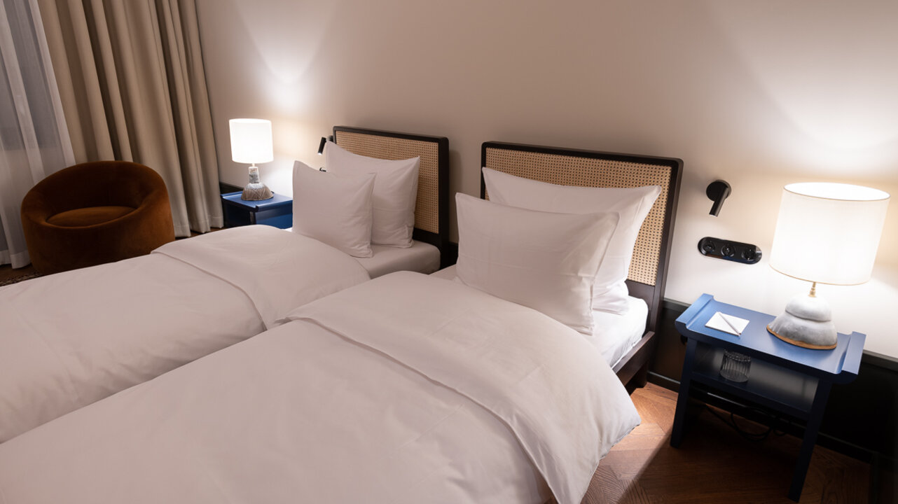 View of the small bedroom with twin beds and two blue nightstands in a family room at the Château Royal.