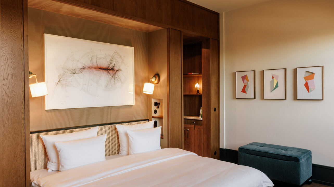 Ansicht einer Junior Suite im Hotel Château Royal Berlin mit einem großen Bett und Kunstwerken von Jorinde Voigt.
