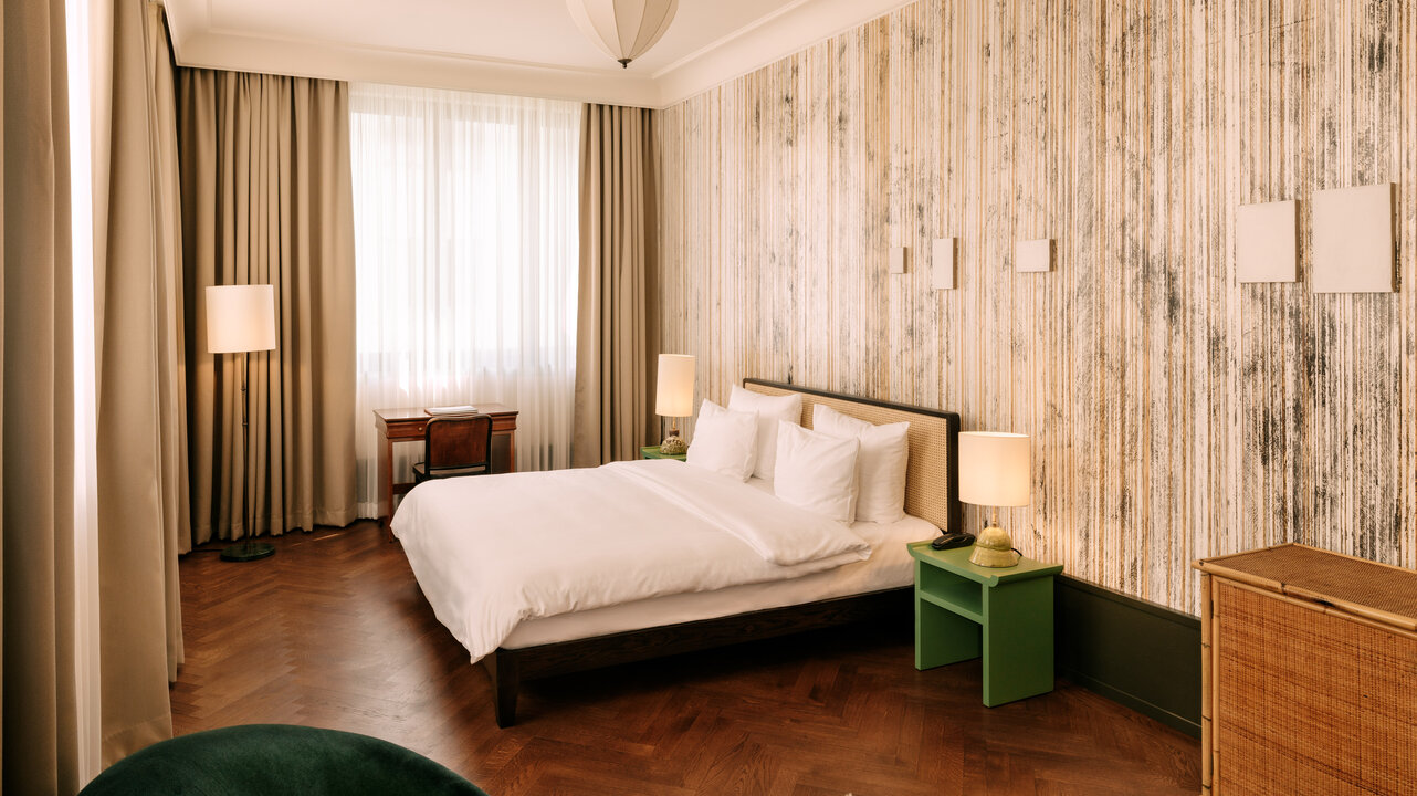 Ansicht des Schlafbereichs in einem großzügigen und lichtdurchfluteten Hotelzimmer im Boutiquehotel Chateau Royal Berlin.