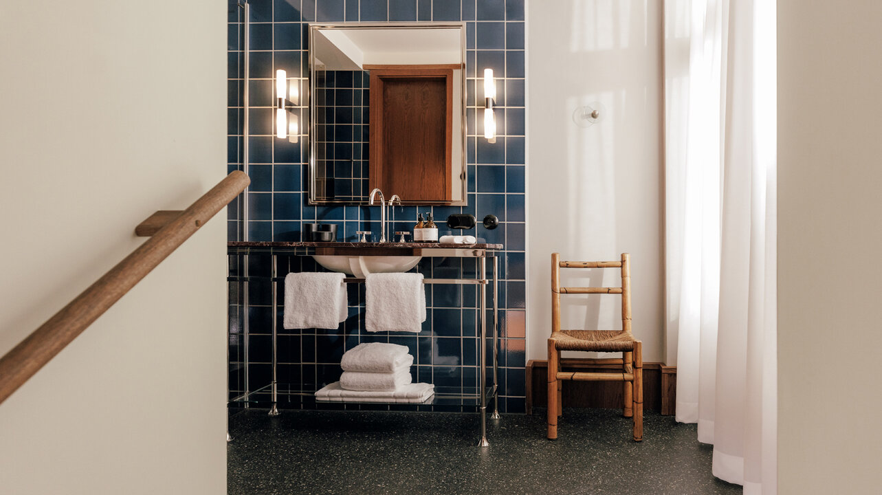 Blick auf das Waschbecken mit Spiegel im Bad eines großen Hotelzimmers im Boutiquehoel Château Royal in Berlin Mitte.