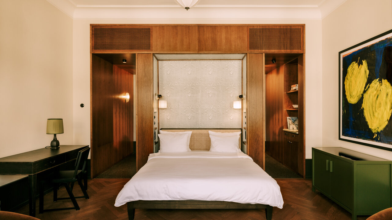 View of the large bed in a suite in the boutique hotel Château Royal, with an artwork by Helmut Middendorf on the right wall