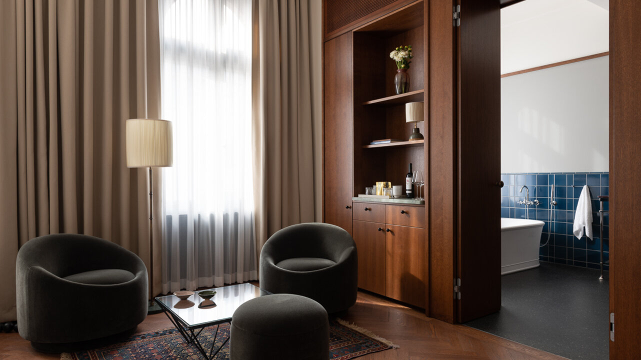 View of the sitting area by the window of a suite at the boutique hotel Château Royal, which has armchairs and a Persian carpet.