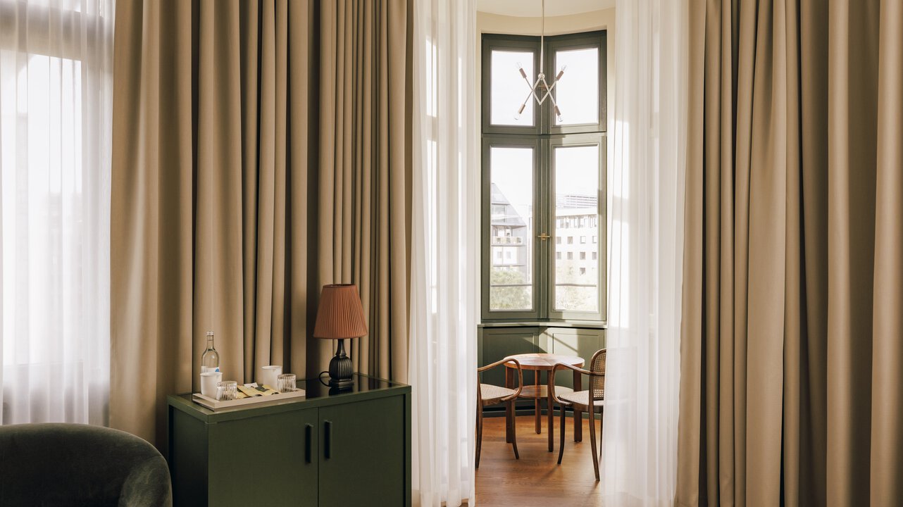 Blick auf den Erker der Tower Suite im Château Royal Berlin, ausgestattet mit einem kleinen Tisch und zwei Stühlen.