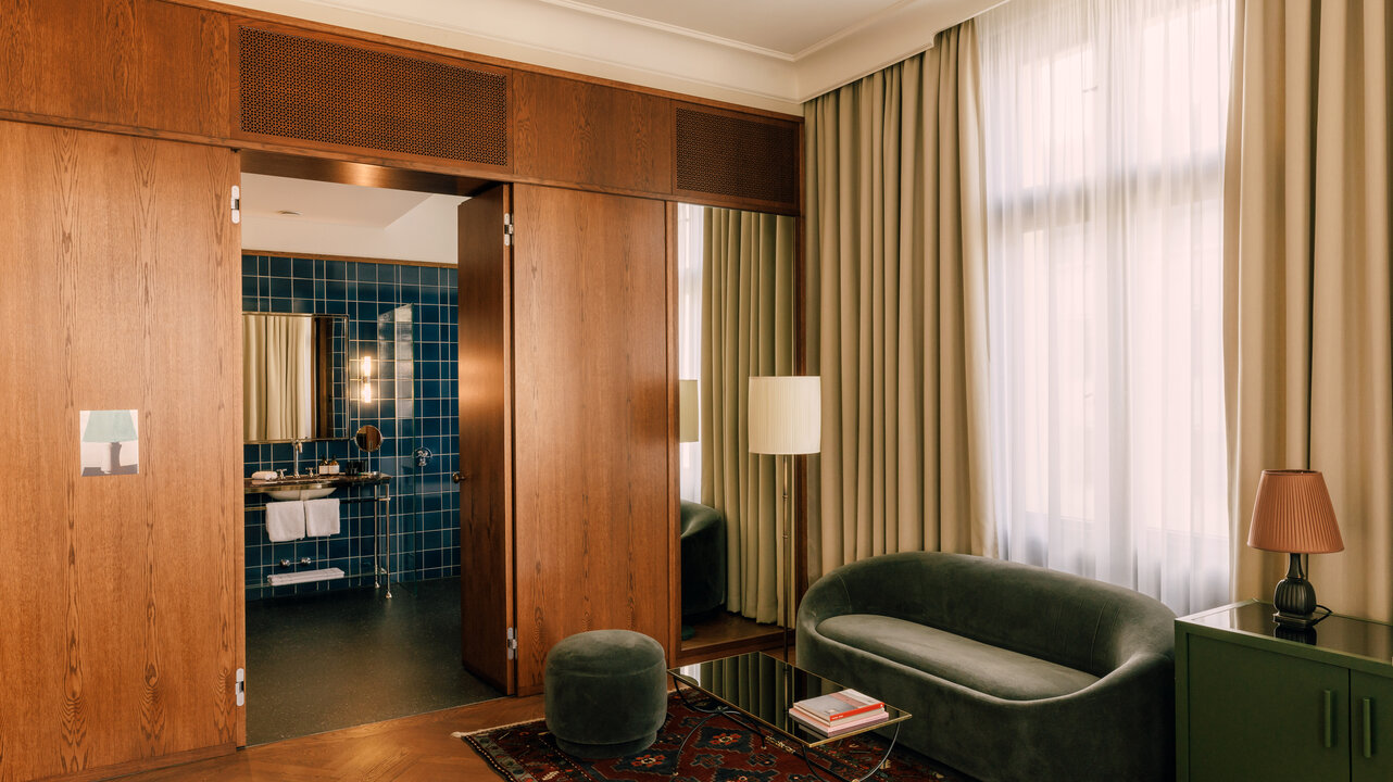 Der Wohnbereich einer Tower Suite im Boutiquehotel Château Royal, mit einer grünen Couch, einem Tisch und einem persischen Teppich.