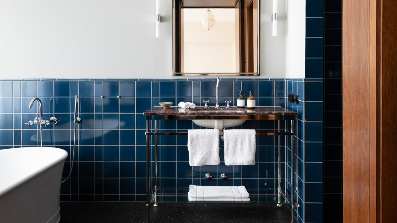 View of the sink in the bathroom of the Tower Suite at Château Royal, which has dark blue tiles.