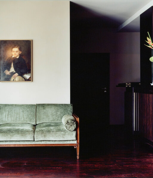 View of a historic green velvet sofa under the painting of a boy at the restaurant Grill Royal
