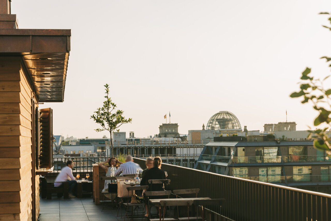 Relaxed evening atmosphere with a view of the Reichstag building from the roof terrace of the Château Royal Bar in Berlin Mitte