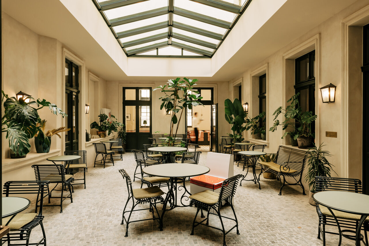 Blick in den begrünten, mit eleganten Terrassenmöbeln ausgestatteten Wintergarten des Château Royal, der als Eventlocation in Berlin Mitte zur Verfügung steht