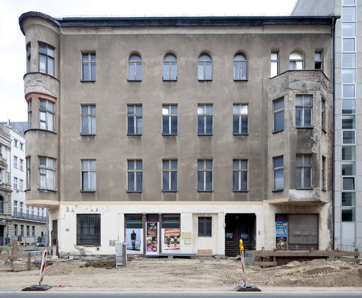 View of the run-down facade of the corner building without any stucco left in 2010.