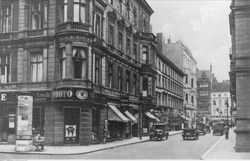 Foto des Eckgebäudes Neustädtische Kirchstraße 3 im Jahr 1936 mit alten Autos, die Richtung Unter den Linden fahren.