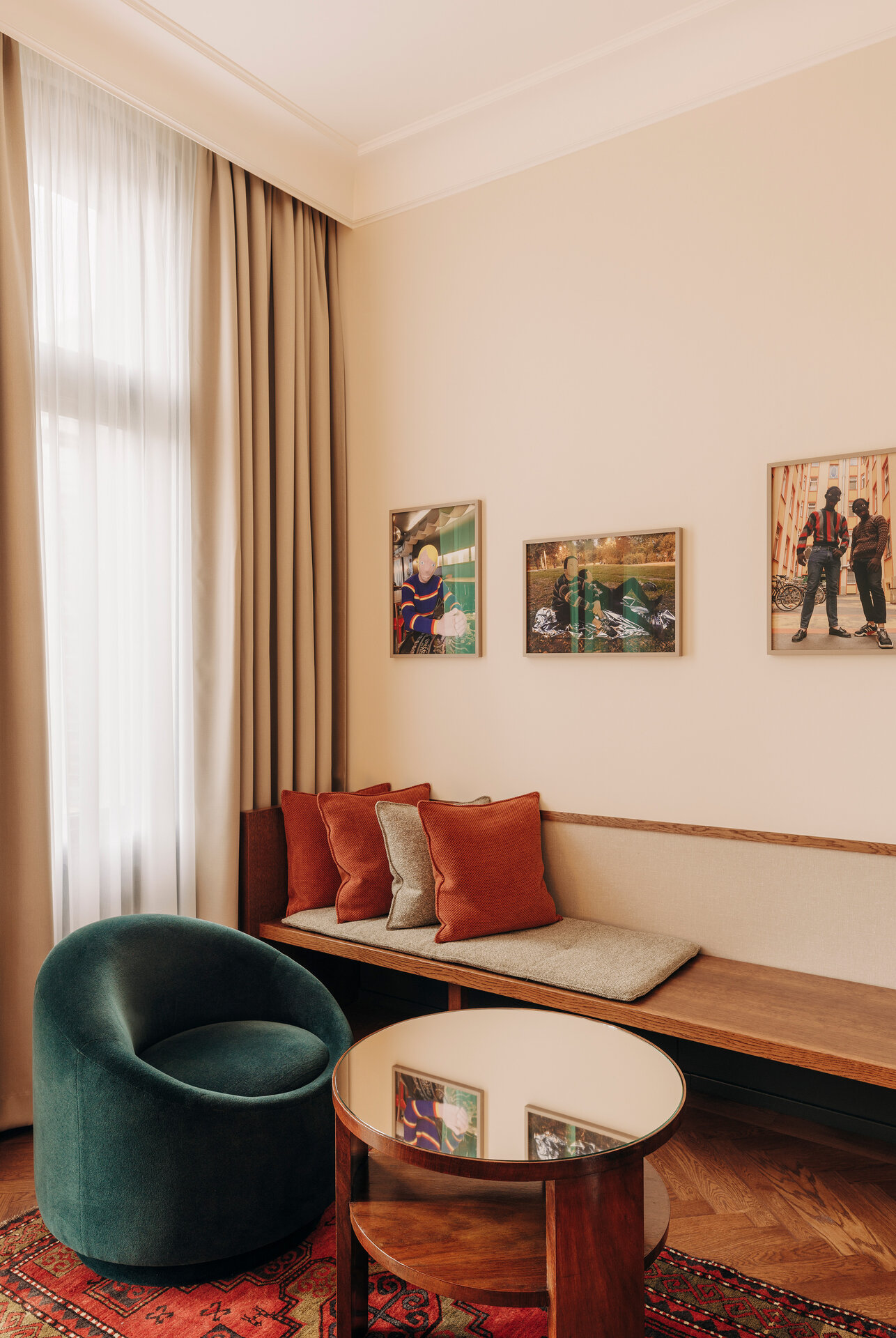 View of the cosy seating area with a small green armchair and a bench with cushions in front of a large window in a hotel room at the boutique hotel Château Royal Berlin