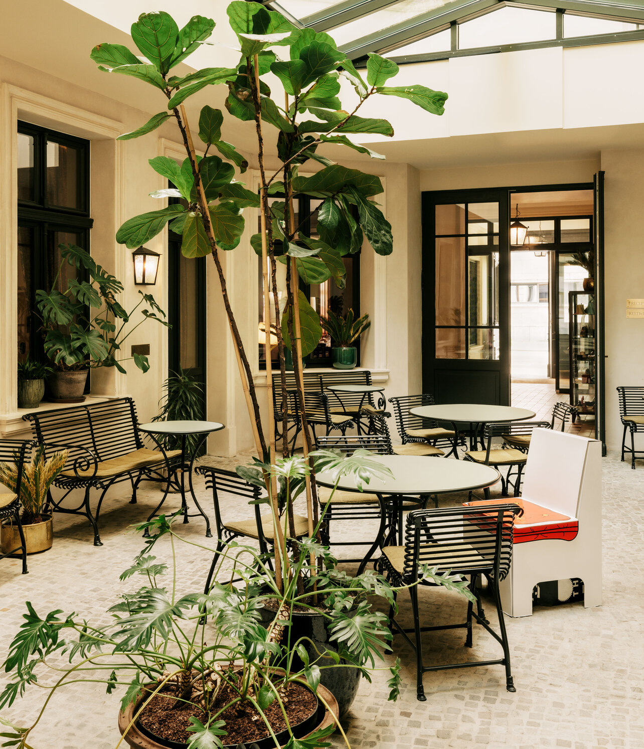 The light-flooded winter garden of the boutique hotel Château Royal Berlin with elegant terrace furniture and decorated with various exotic plants