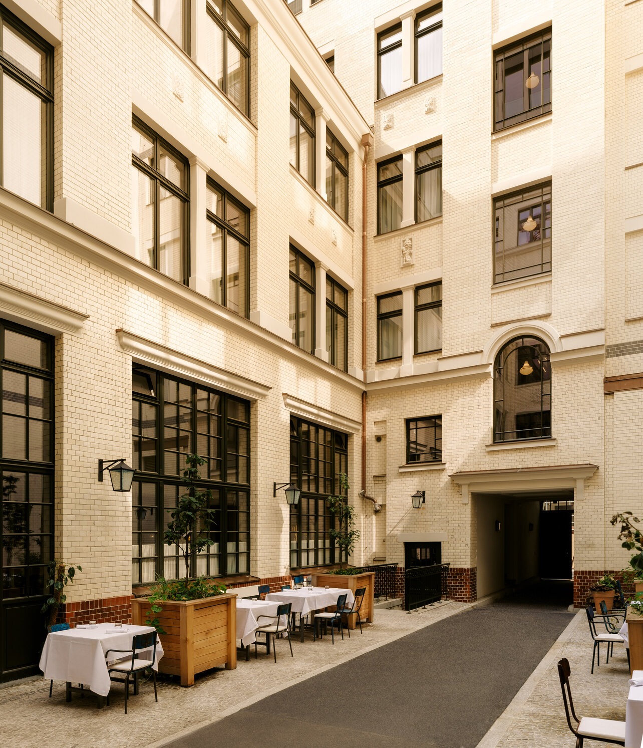 Blick in den charmanten historischen Innenhof des Restaurants Château Royal in Berlin Mitte mit elegant in weiß gedeckten Tischen