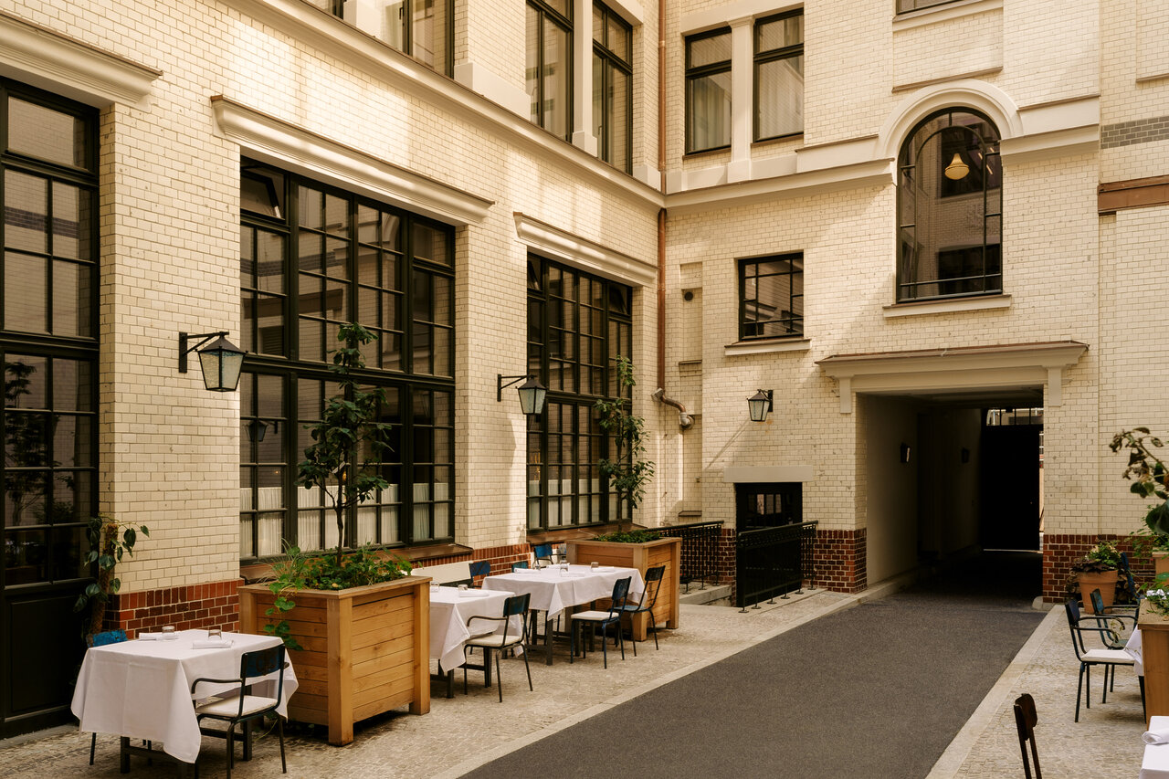 Blick in den charmanten historischen Innenhof des Restaurants Château Royal in Berlin Mitte mit elegant in weiß gedeckten Tischen