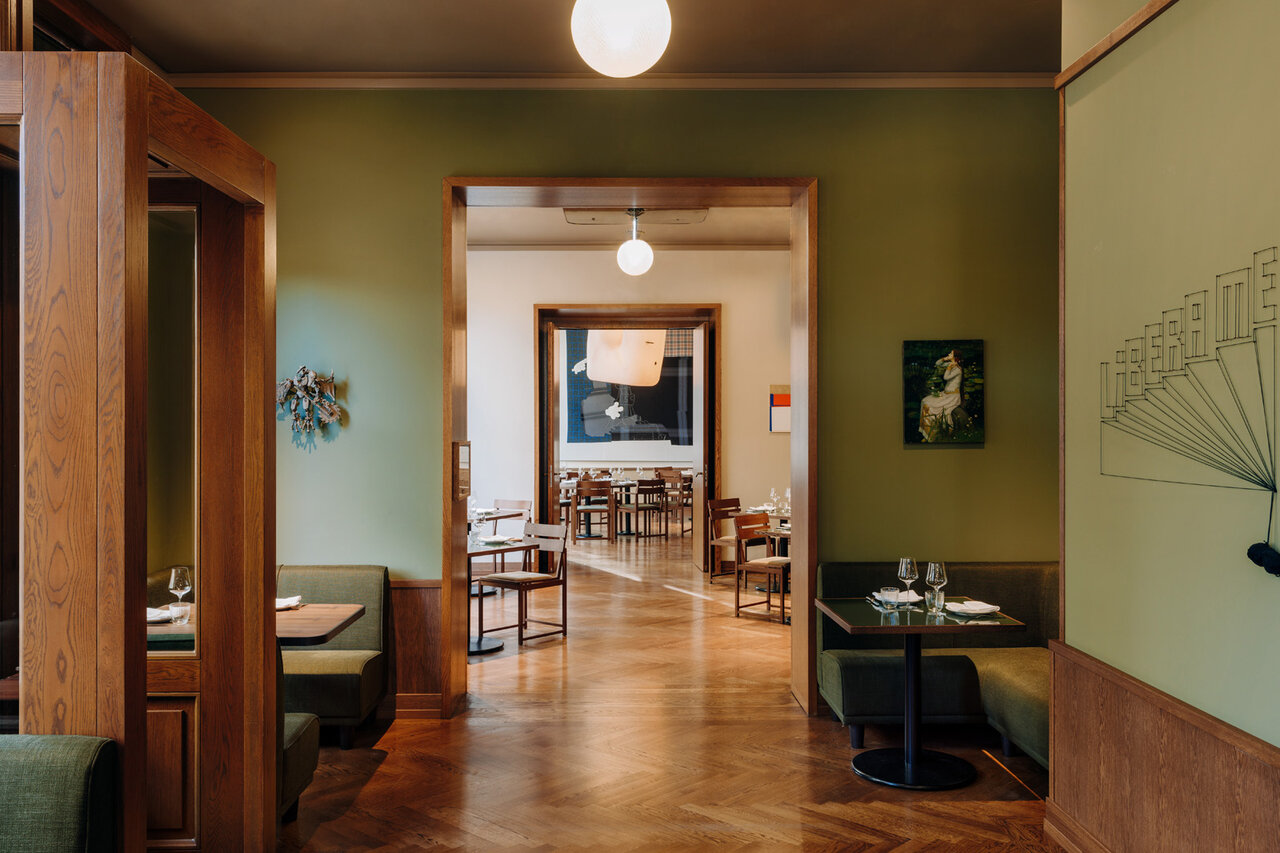 Blick auf den Gang des Restaurants im Boutiquehotel Château Royal Berlinmit Sitzmöglichkeiten und dekoriert mit verschiedenen Kunstwerken.